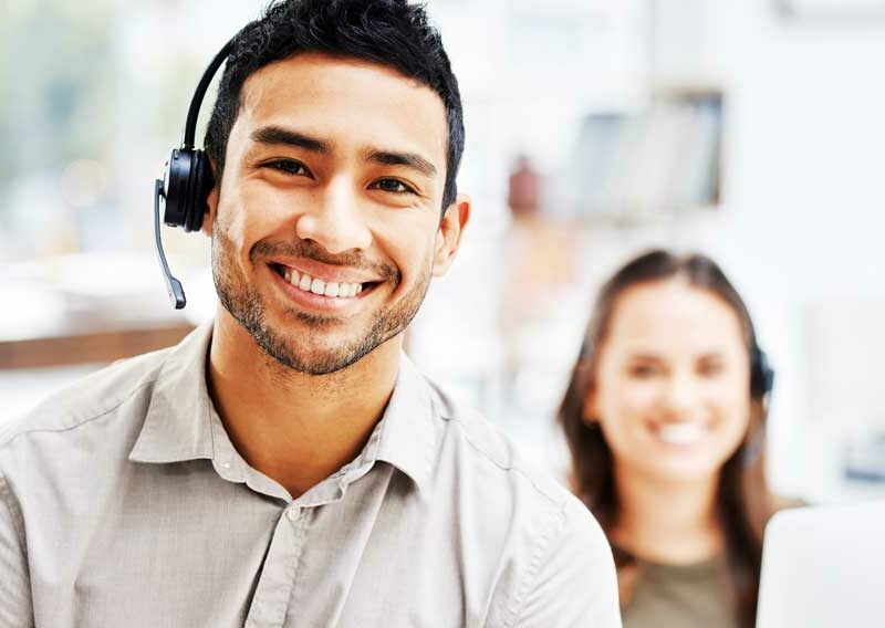 Ein Service Desk Mitarbeiter und ein Service Desk Mitarbeiterin lächeln in die Kamera