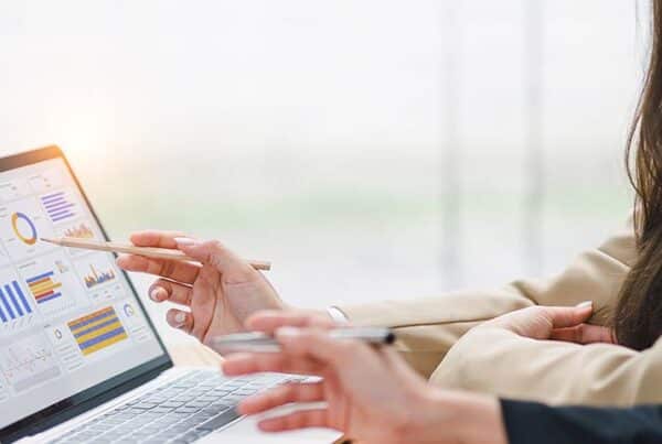 Dynamics 365 Business Central – Finanzprozesse effizient gestalten: 2 Personen sitzen vor Laptop und sehen sich Finanzbericht an