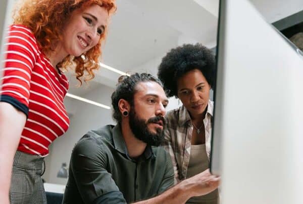 SharePoint-Migration in die Cloud – Sichere Umsetzung in 5 Schritten: 3 Kollegen sitzen vor einem PC und besprechen sich